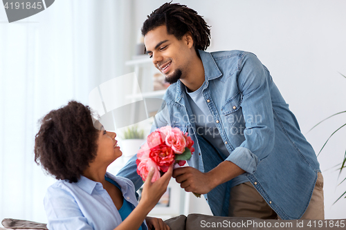 Image of happy couple with bunch of flowers at home