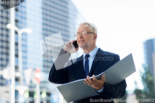 Image of senior businessman calling on smartphone in city