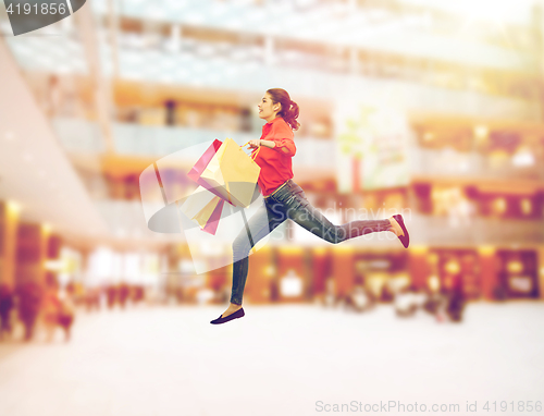 Image of smiling young woman with shopping bags jumping