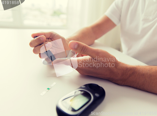 Image of close up of man checking blood sugar by glucometer