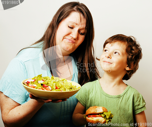 Image of mature woman holding salad and little cute boy with hamburger te