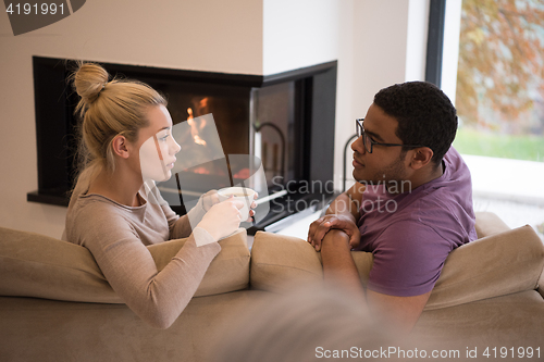 Image of Young multiethnic couple  in front of fireplace