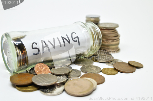 Image of Saving lable in a glass jar with coins spilling out