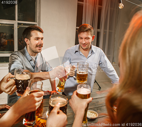 Image of Group of friends enjoying evening drinks with beer