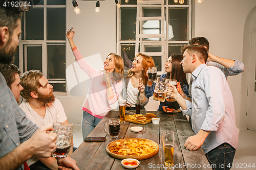 Image of Group of friends enjoying evening drinks with beer