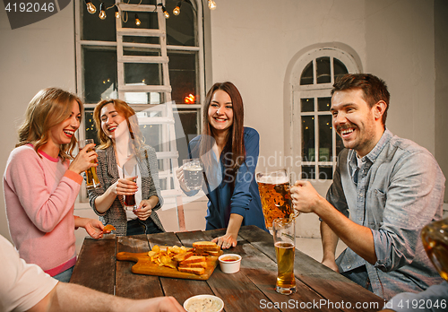 Image of Group of friends enjoying evening drinks with beer