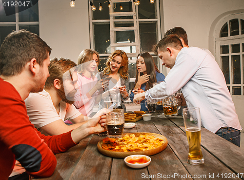 Image of Group of friends enjoying evening drinks with beer