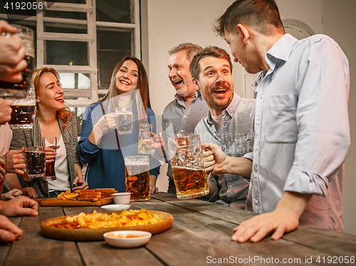 Image of Group of friends enjoying evening drinks with beer