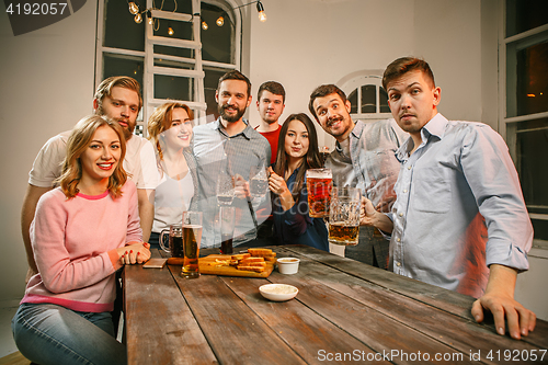 Image of Group of friends enjoying evening drinks with beer