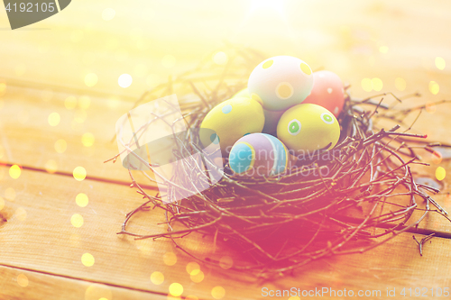 Image of close up of colored easter eggs in nest on wood