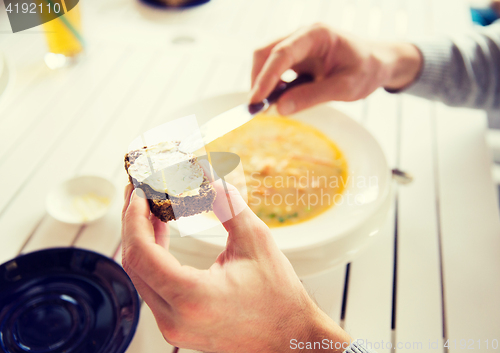 Image of close up of hands applying butter to bread