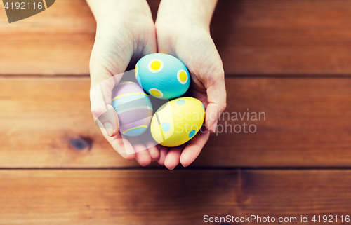 Image of close up of woman hands with colored easter eggs