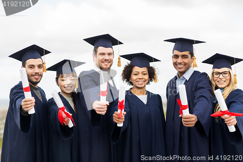 Image of happy students in mortar boards with diplomas