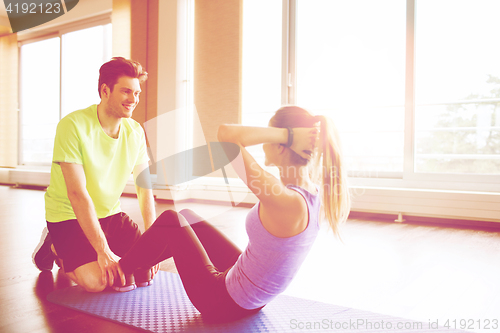 Image of woman with personal trainer doing sit ups in gym