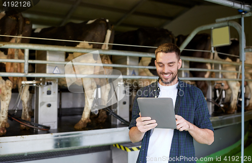 Image of young man with tablet pc and cows on dairy farm