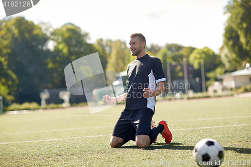 Image of happy soccer player with ball on football field