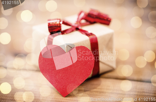 Image of close up of gift box and heart shaped note on wood