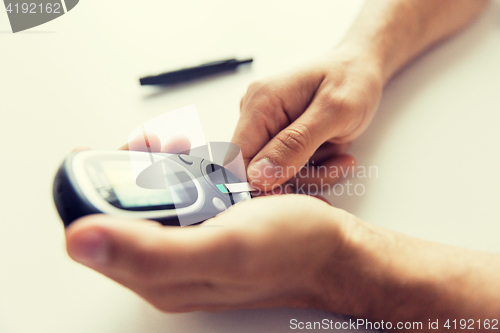 Image of close up of man checking blood sugar by glucometer