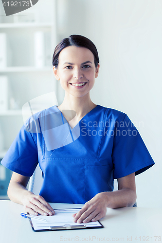 Image of happy doctor or nurse with clipboard at hospital