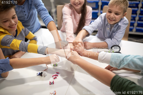 Image of happy children making fist bump at robotics school