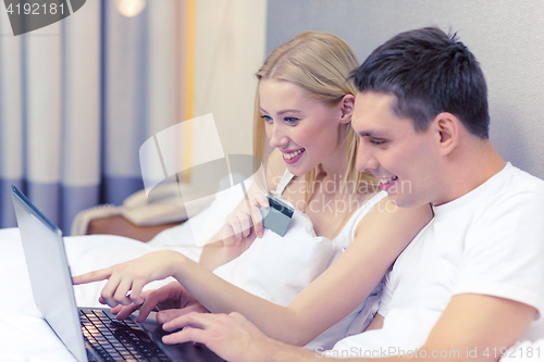 Image of couple in bed with laptop computer and credit card