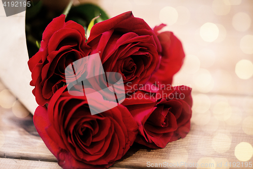 Image of close up of red roses bunch wrapped into paper