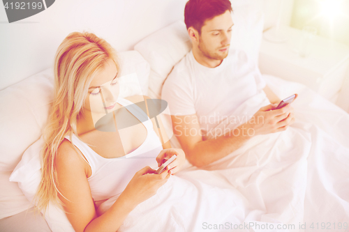 Image of couple with smartphones in bed