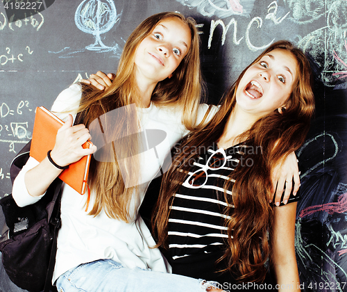 Image of back to school after summer vacations, two teen real girls in classroom with blackboard painted together, lifestyle people concept close up