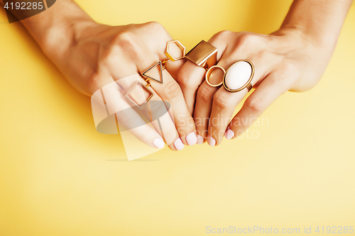 Image of woman hands with manicure and jewelry ring on yellow background, beauty style concept