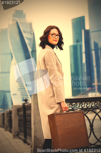 Image of businesswoman in a bright coat and a wooden case