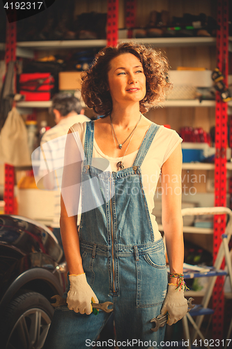 Image of beautiful smiling middle-aged woman with wrenches in her hands