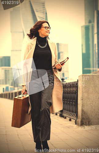 Image of beautiful smiling middle-aged woman in a bright coat goes with a