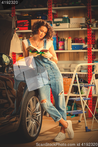 Image of woman in blue overalls studying the instructions for vehicle adj