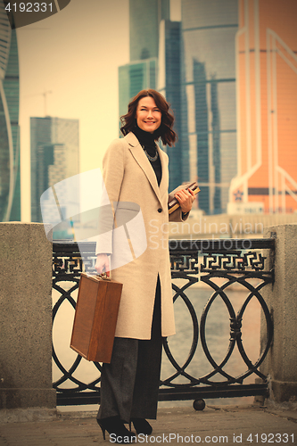 Image of brunette with a wooden case and books in her hands