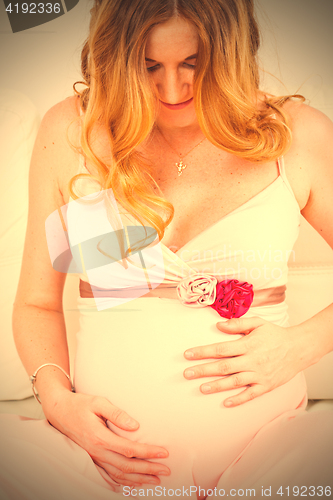 Image of Beautiful pregnant woman looks at the belly