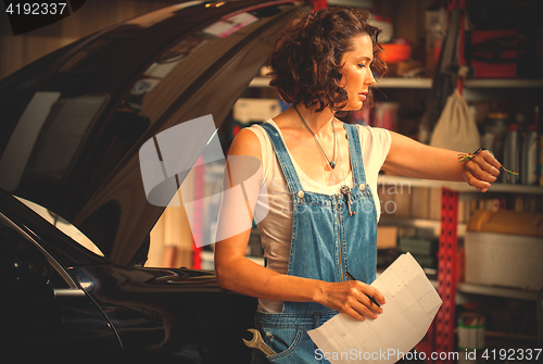 Image of beautiful woman car mechanic in blue overalls