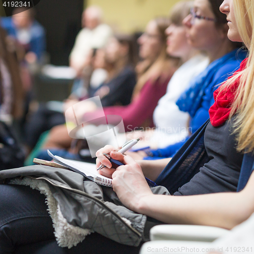 Image of Hands holding pens and making notes at conference lecture.