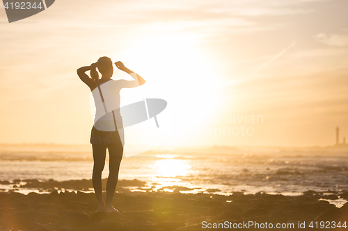 Image of Woman on sandy beach watching sunset.