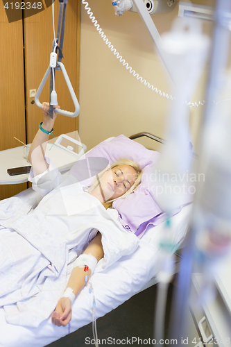 Image of Bedridden female patient recovering after surgery in hospital care.