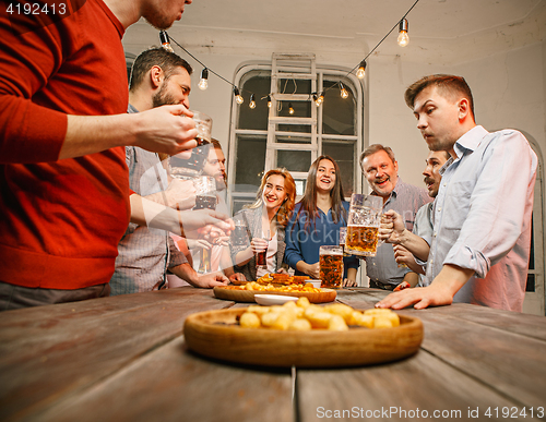 Image of Group of friends enjoying evening drinks with beer