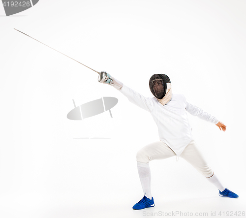 Image of Man wearing fencing suit practicing with sword against gray