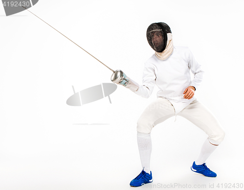 Image of Man wearing fencing suit practicing with sword against gray