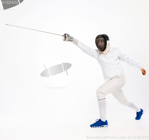 Image of Man wearing fencing suit practicing with sword against gray