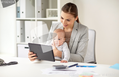 Image of businesswoman with baby and tablet pc at office