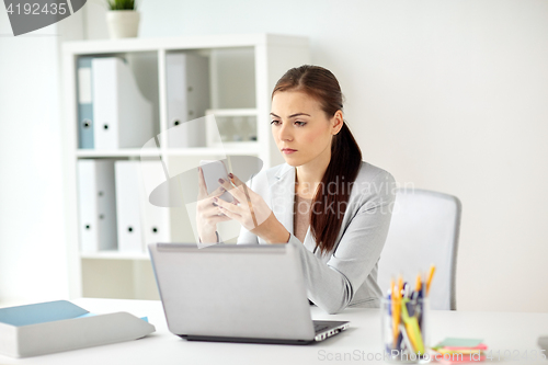 Image of businesswoman with smartphone at office