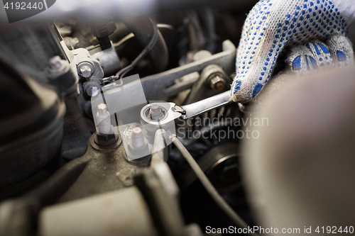 Image of mechanic man with wrench repairing car at workshop