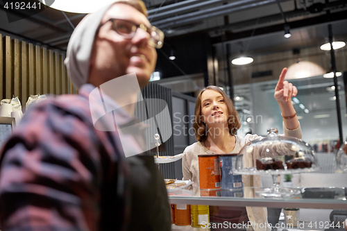 Image of happy woman showing something to bartender at cafe