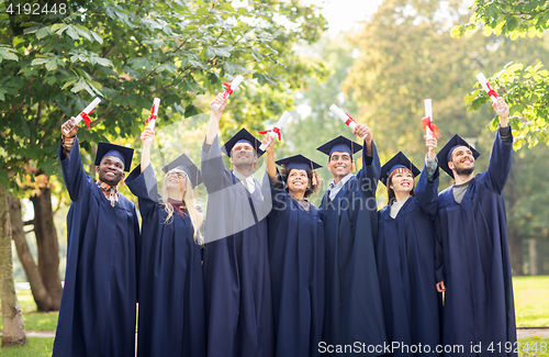 Image of happy students in mortar boards with diplomas