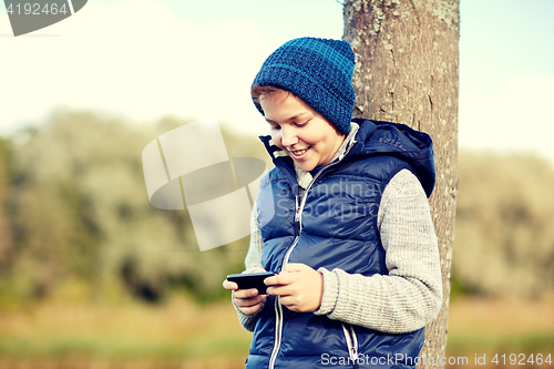 Image of happy boy playing game on smartphone outdoors