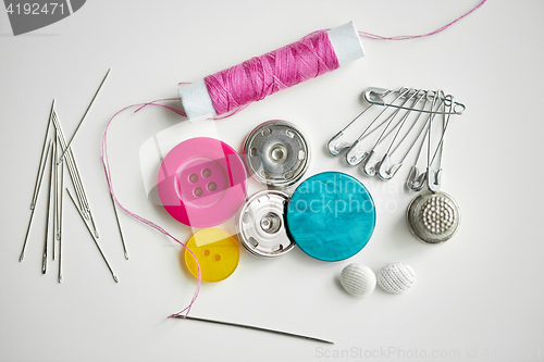 Image of sewing buttons, needles, pins and thread spool